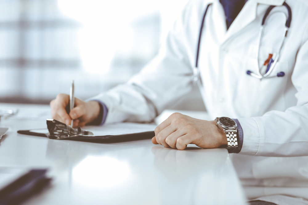Unknown,Male,Doctor,Sitting,And,Working,With,Clipboard,Of,Medication